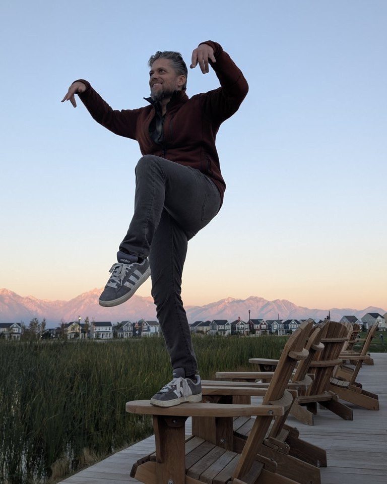 Ben Page on a dock at sunset, one leg up, arms out, doing the crane kick.