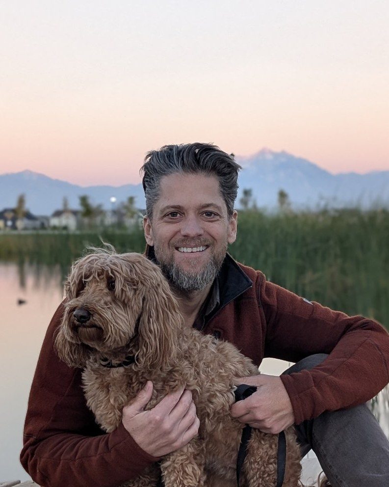 Ben Page with his dog on a dock at dusk.